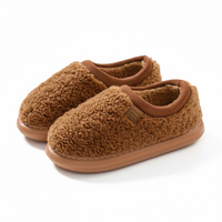 A pair of cozy slip-on fleece house slippers in a warm brown color, featuring a soft textured sherpa upper and a smooth rubber sole, shown on a clean white background.