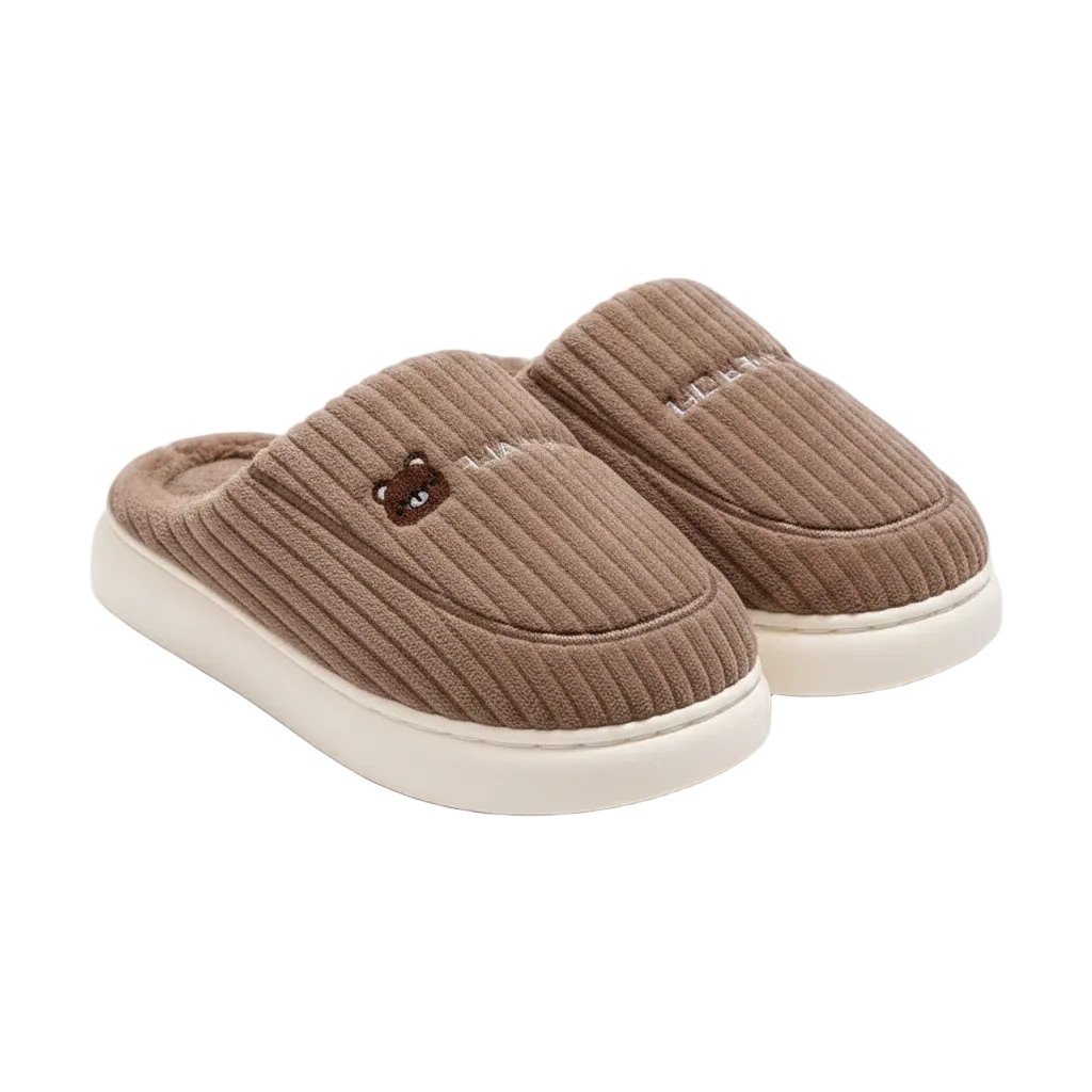 A pair of brown ribbed knit slip-on slippers with cream-colored soles and a small embroidered bear face on the side, shown on a clean white background.