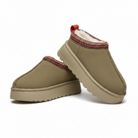 A pair of slip-on winter slippers in a muted olive-tan color, featuring a soft cream fleece lining, a red and beige patterned collar trim, and a thick platform sole, shown on a clean white background.