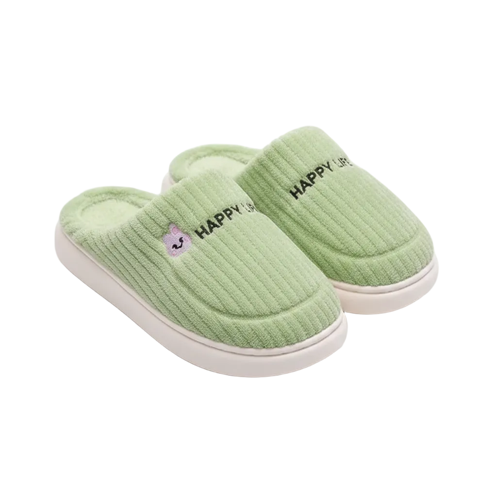 A pair of light green ribbed knit slip-on slippers with white soles, featuring 'HAPPY' embroidered in black on the side and a small purple cartoon face logo.