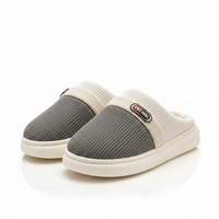 A pair of slip-on mule slippers with a textured gray upper and cream ribbed trim and sole, shown on a clean white background.