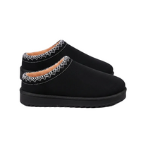 A pair of black slip-on clogs with white geometric embroidered trim around the collar and a tan lining, shown against a plain white background.