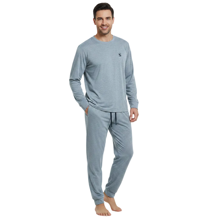 A man modeling a light blue-gray long-sleeve crewneck shirt and matching jogger pants with a drawstring, shown against a plain white background.