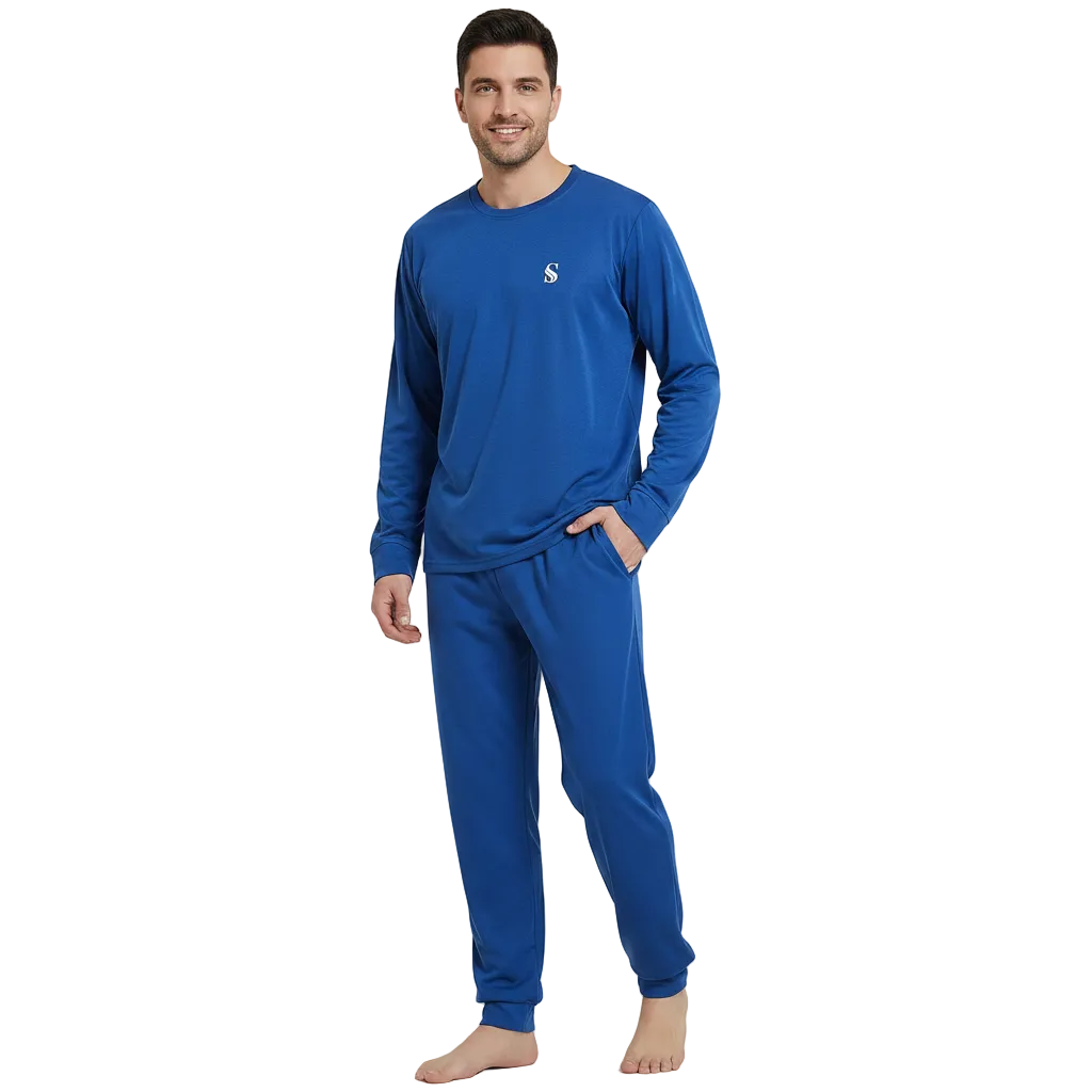 A man modeling a matching royal blue long-sleeve pajama top and jogger pants set against a light gray studio background.