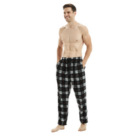 A shirtless man wearing black, white, and red plaid pajama pants, standing against a plain white studio background.