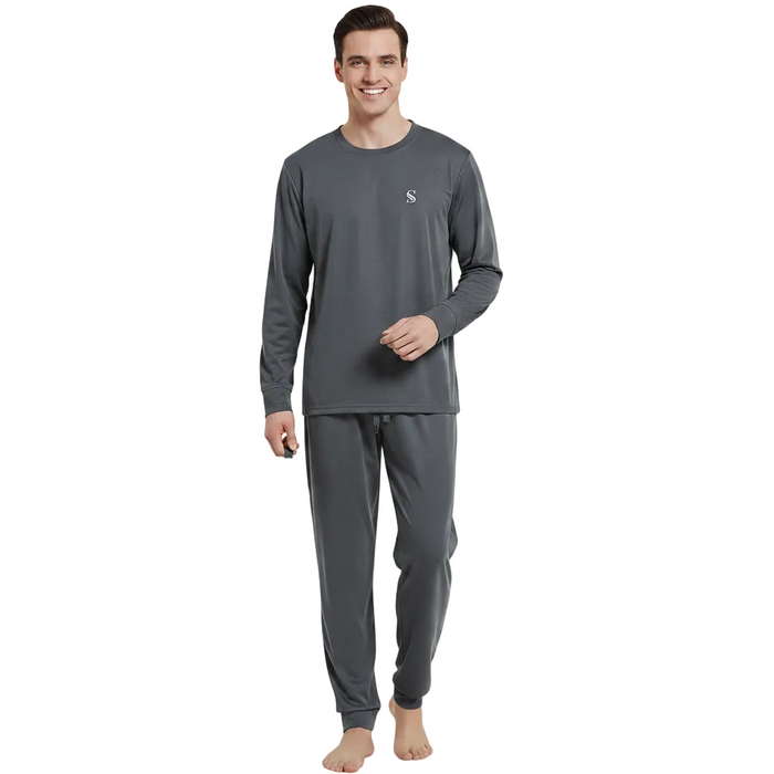 A man modeling a dark gray long-sleeve pajama set with matching jogger pants and a small white embroidered logo on the chest, standing against a plain white background.