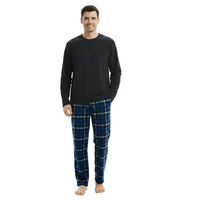 A man modeling a two-piece pajama set consisting of a solid black long-sleeve shirt and blue plaid pants with white and thin yellow stripes, shot against a plain white background.