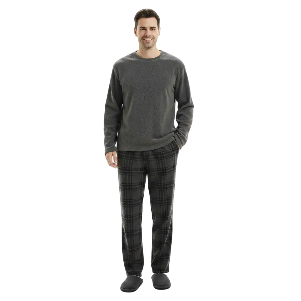 A man modeling a dark gray long-sleeve crewneck shirt and matching dark gray plaid pajama pants with black slippers, shot against a solid white background.