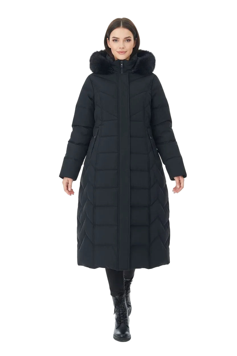 A woman modeling a long black quilted puffer coat with a large faux-fur trimmed hood, photographed against a plain white studio background.