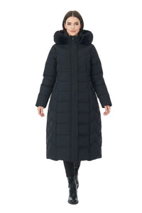 A woman modeling a long black quilted puffer coat with a large faux-fur trimmed hood, photographed against a plain white studio background.