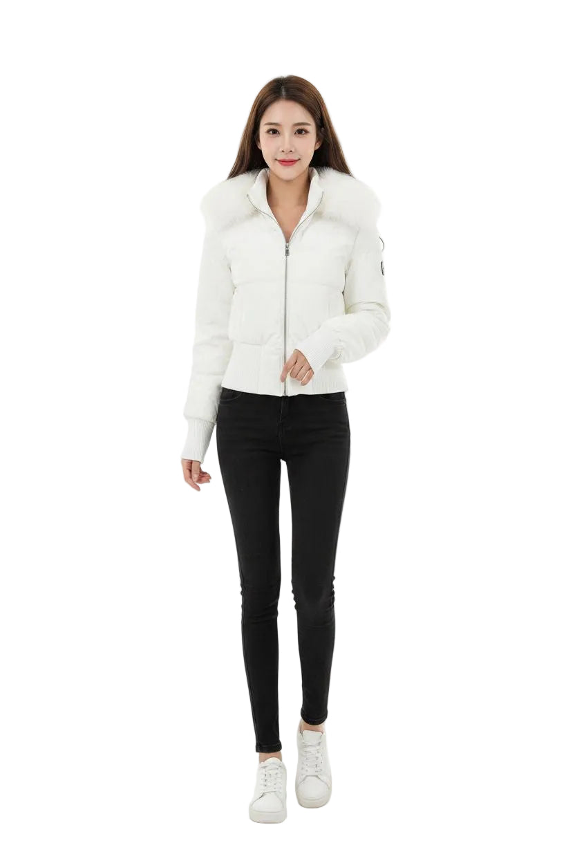 A woman modeling a white cropped puffer jacket with a large faux-fur collar, paired with black skinny jeans and white sneakers, against a plain white studio background.