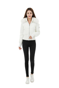 A woman modeling a white cropped puffer jacket with a large faux-fur collar, paired with black skinny jeans and white sneakers, against a plain white studio background.