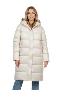 A woman wearing a long, hooded puffer coat in a light cream or off-white color, paired with blue jeans, photographed against a seamless white studio background.