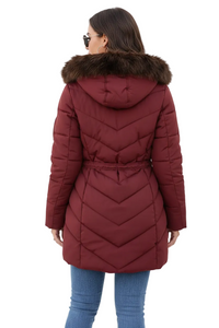 A woman shown from the back wearing a burgundy quilted puffer coat with a brown faux-fur trimmed hood and a drawstring waist, paired with blue jeans, against a plain white studio background.