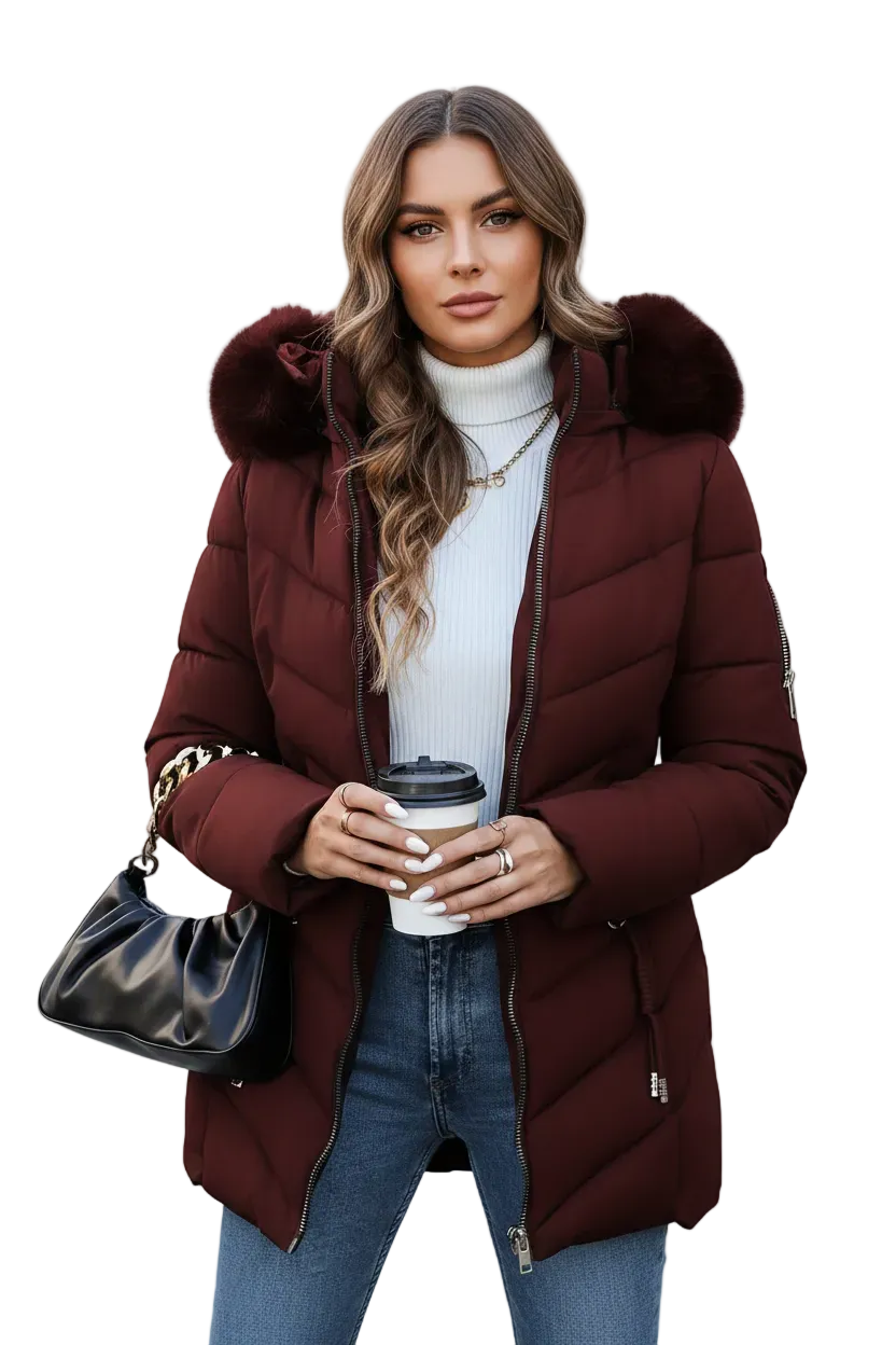 A woman modeling a long burgundy puffer coat with a faux-fur trimmed hood, worn over a white ribbed turtleneck and blue jeans, holding a black coffee cup and a black handbag against a plain white background.
