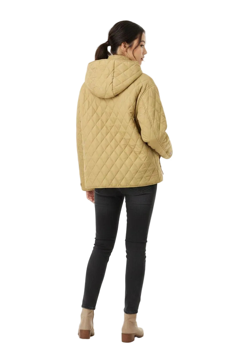 A woman shown from the back wearing a quilted hooded jacket in a warm tan color, paired with black skinny pants and beige ankle boots, against a plain white studio background.